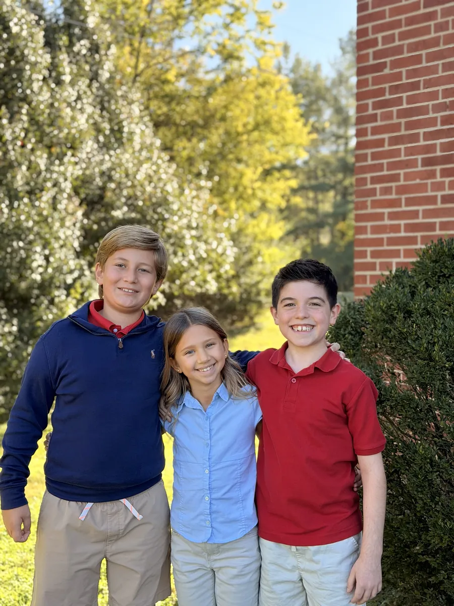 Three smiling Anchor Christian students standing together outside the co-op campus